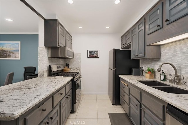 kitchen featuring light stone countertops, decorative backsplash, stainless steel appliances, sink, and light tile patterned floors