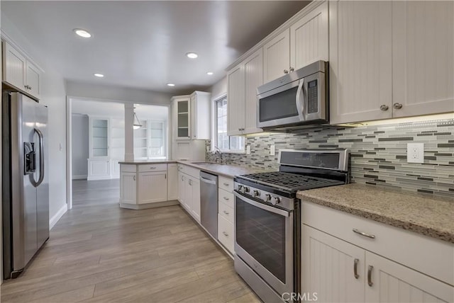 kitchen featuring white cabinetry, sink, stainless steel appliances, light stone counters, and light hardwood / wood-style flooring