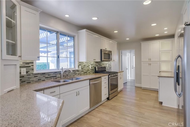 kitchen featuring white cabinetry, sink, stainless steel appliances, and light wood-type flooring