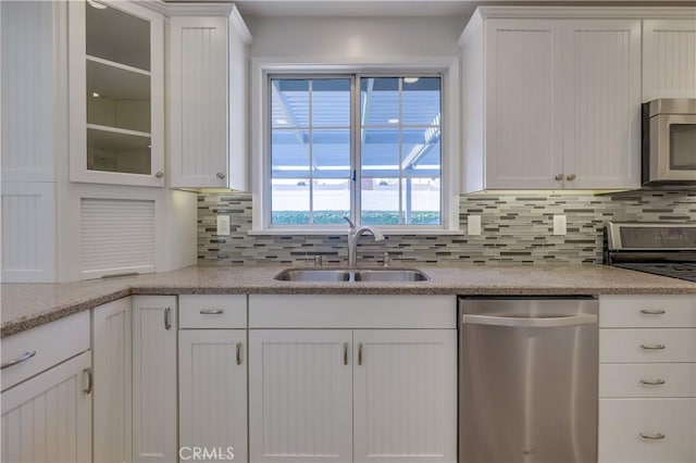 kitchen with appliances with stainless steel finishes, backsplash, white cabinetry, and sink