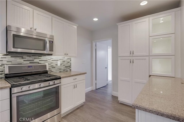 kitchen with light wood-type flooring, stainless steel appliances, and white cabinetry