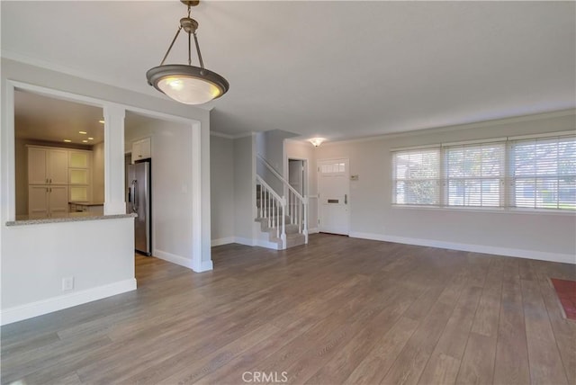 unfurnished living room with hardwood / wood-style flooring and crown molding