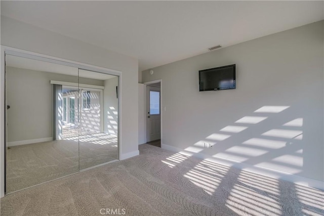 unfurnished bedroom featuring carpet floors, a closet, and a notable chandelier