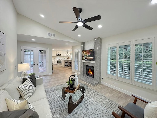 living room featuring french doors, light wood-type flooring, ceiling fan, and lofted ceiling