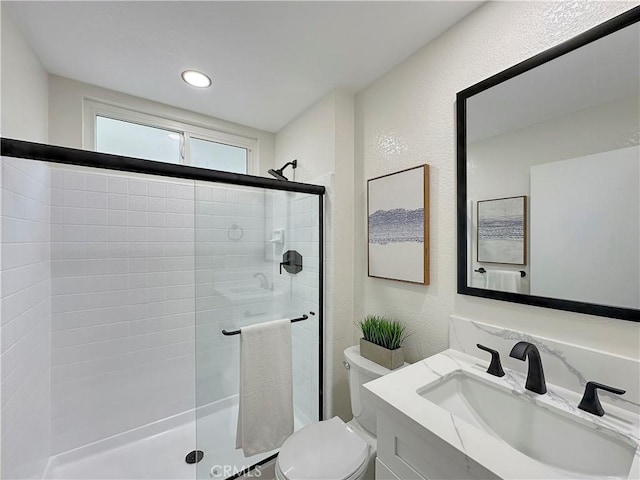 bathroom featuring vanity, toilet, and a shower with shower door