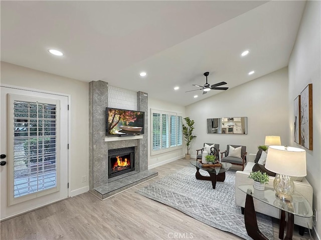 living room with ceiling fan, a fireplace, wood-type flooring, and vaulted ceiling