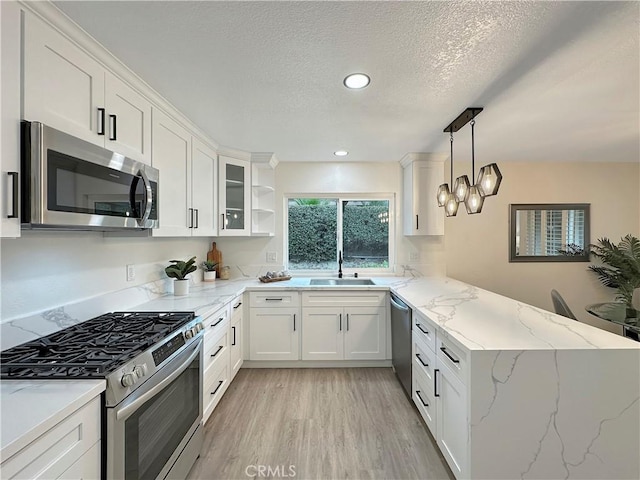 kitchen with kitchen peninsula, white cabinets, stainless steel appliances, and decorative light fixtures