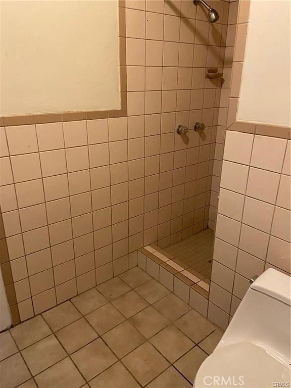 bathroom featuring a tile shower, tile patterned floors, tile walls, and toilet