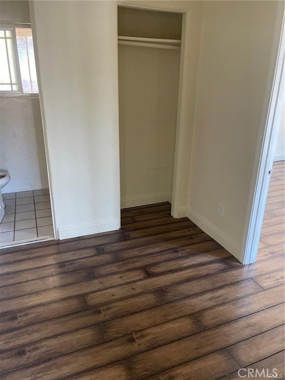 unfurnished bedroom featuring a closet and dark hardwood / wood-style floors