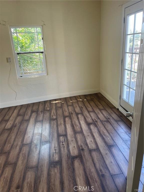 unfurnished room featuring plenty of natural light and dark hardwood / wood-style flooring