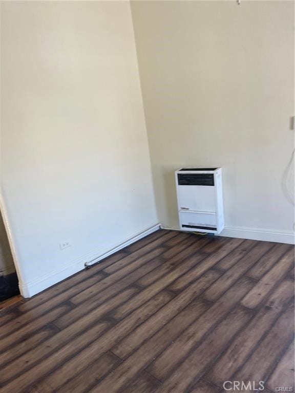 unfurnished room with dark hardwood / wood-style flooring and heating unit