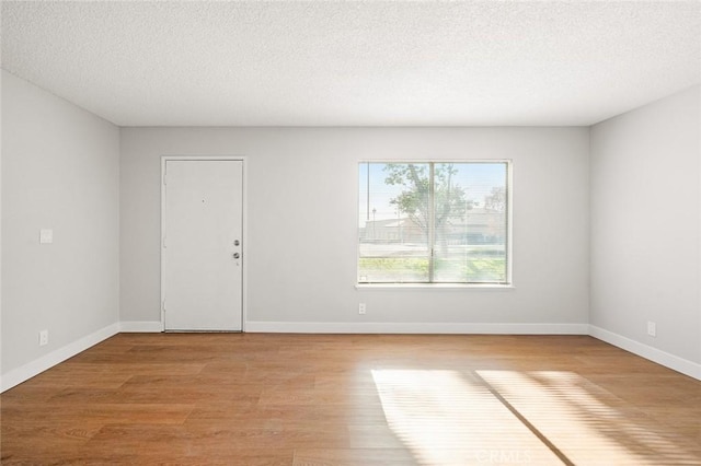 spare room with light hardwood / wood-style flooring and a textured ceiling