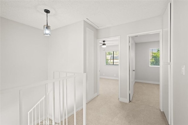 hallway featuring a textured ceiling and light colored carpet