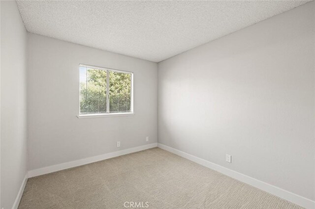 unfurnished room with a textured ceiling and light colored carpet