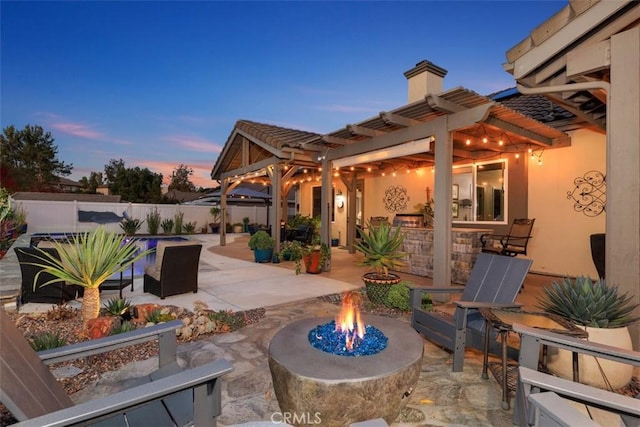 patio terrace at dusk with a pergola and an outdoor fire pit