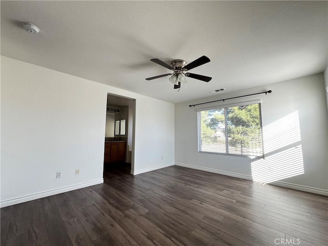 empty room featuring a textured ceiling, ceiling fan, and dark wood-type flooring