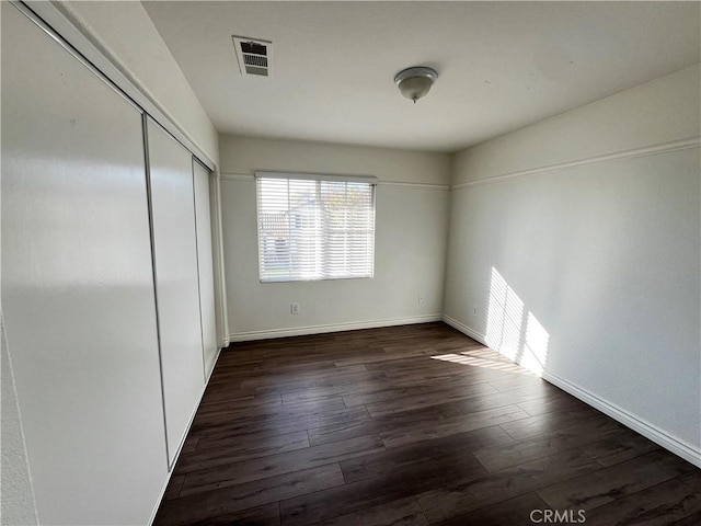 unfurnished bedroom with a closet and dark hardwood / wood-style floors