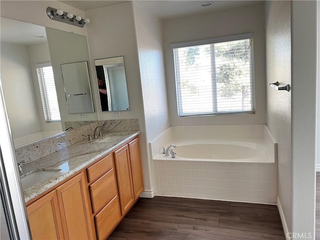 bathroom with tiled bath, hardwood / wood-style floors, and vanity