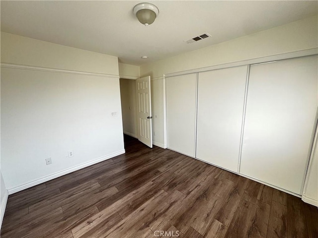 unfurnished bedroom featuring dark hardwood / wood-style floors and a closet