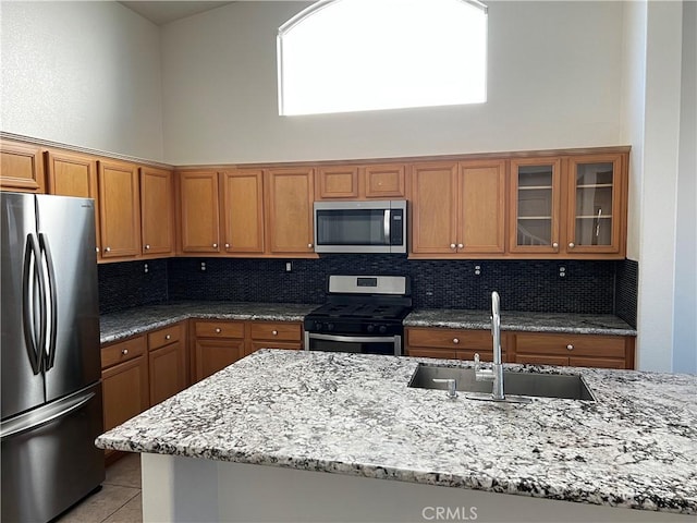 kitchen featuring backsplash, light stone countertops, sink, and appliances with stainless steel finishes