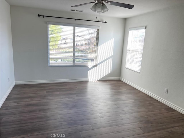 empty room featuring plenty of natural light, dark wood-type flooring, and ceiling fan