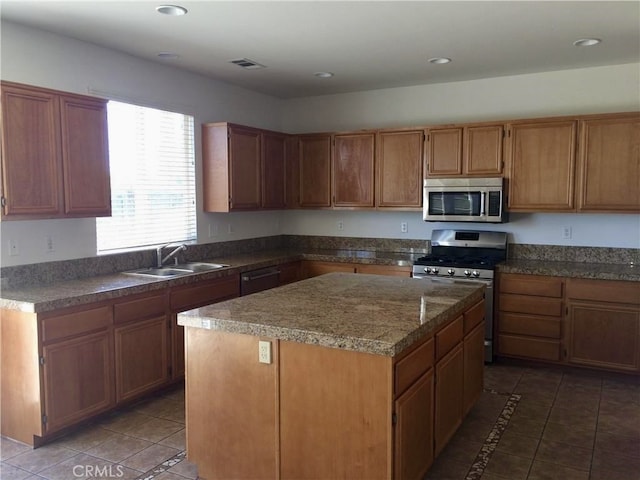 kitchen featuring sink, a kitchen island, stainless steel appliances, and dark tile patterned flooring