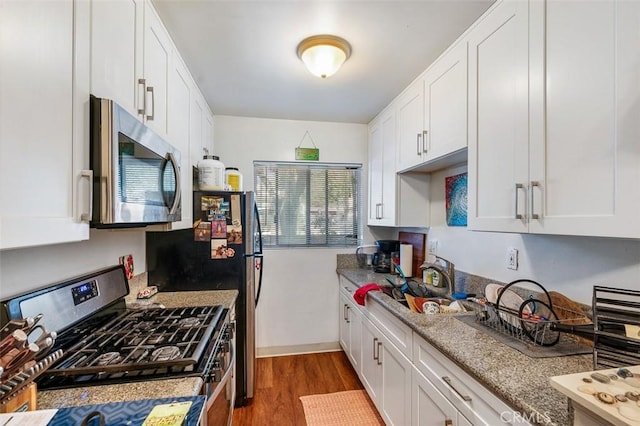 kitchen featuring sink, light wood-type flooring, white cabinetry, light stone countertops, and stainless steel appliances