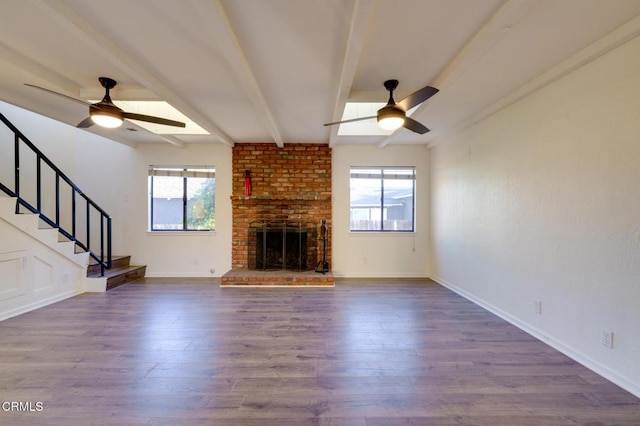 unfurnished living room featuring ceiling fan, a wealth of natural light, and beamed ceiling