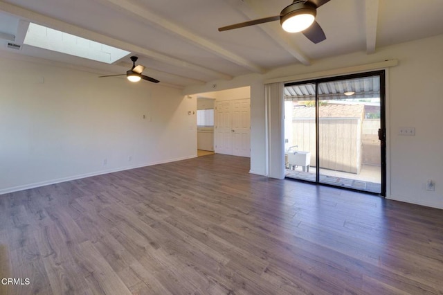 empty room featuring ceiling fan, a skylight, hardwood / wood-style flooring, and beamed ceiling