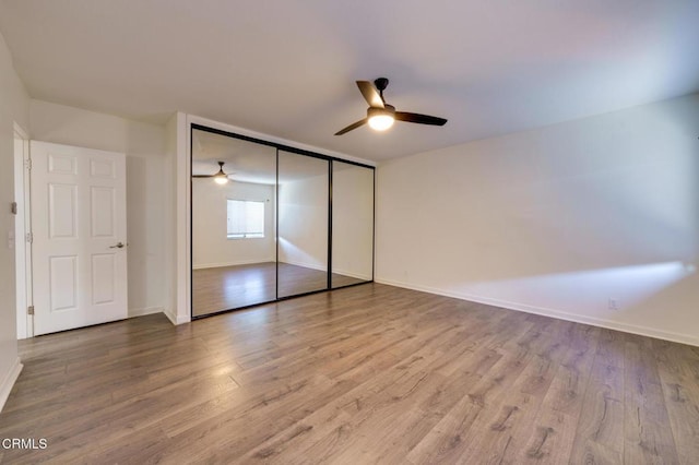 unfurnished bedroom featuring ceiling fan, a closet, and hardwood / wood-style floors