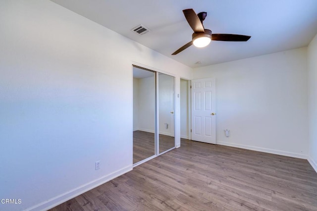 unfurnished bedroom with light wood-type flooring, ceiling fan, and a closet