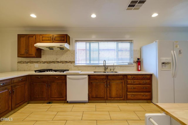 kitchen with crown molding, decorative backsplash, sink, and white appliances