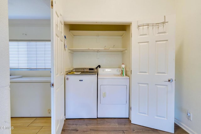 laundry room featuring washer and dryer, ornamental molding, and hardwood / wood-style flooring