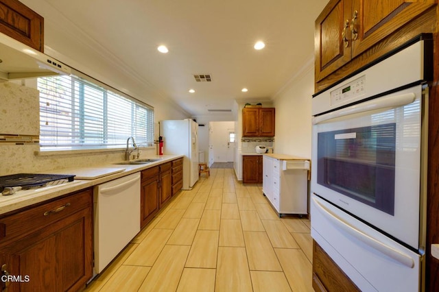 kitchen featuring backsplash, white appliances, sink, and crown molding