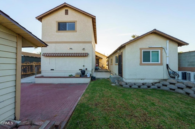 rear view of property featuring ac unit, a lawn, and a patio