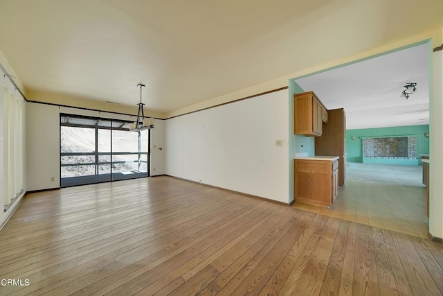 unfurnished living room with light wood-type flooring and a chandelier