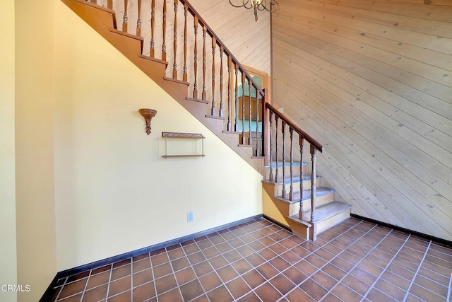 stairs featuring tile patterned flooring and wood walls