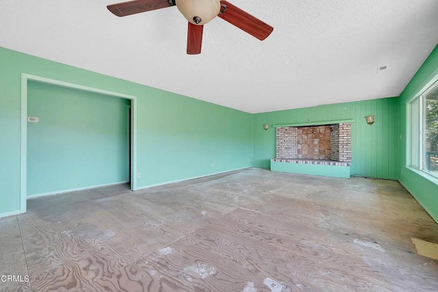 unfurnished living room featuring ceiling fan, a fireplace, and a textured ceiling