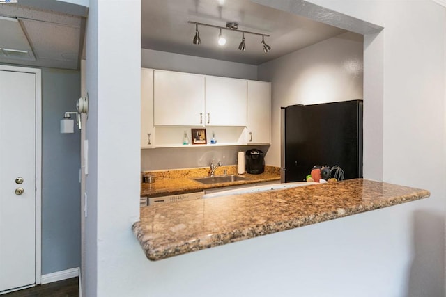 kitchen with black refrigerator, light stone countertops, dark wood-type flooring, sink, and white cabinets