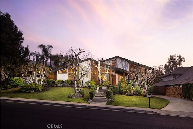 mid-century modern home with driveway and a lawn