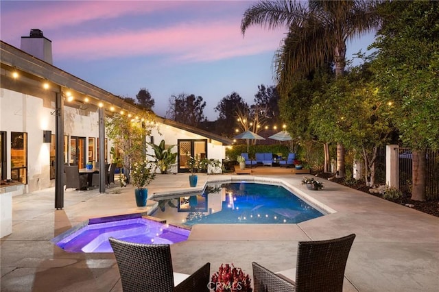 pool at dusk featuring an in ground hot tub, an outdoor living space, and a patio