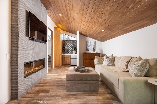 living room featuring a tiled fireplace, wood ceiling, vaulted ceiling, and wood-type flooring