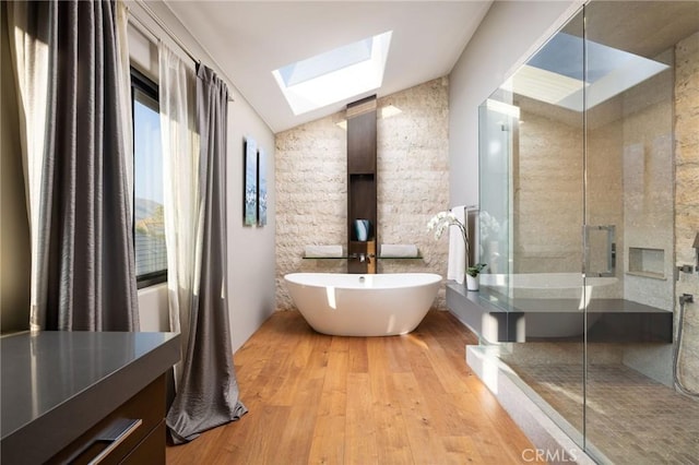 bathroom with vaulted ceiling with skylight, plus walk in shower, and hardwood / wood-style flooring