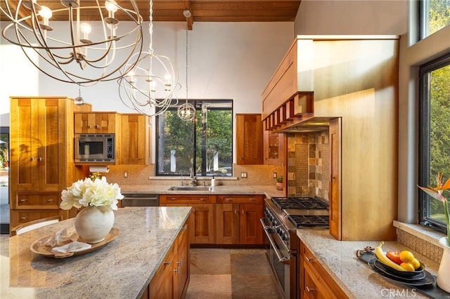 kitchen featuring light stone countertops, backsplash, stainless steel appliances, and an inviting chandelier