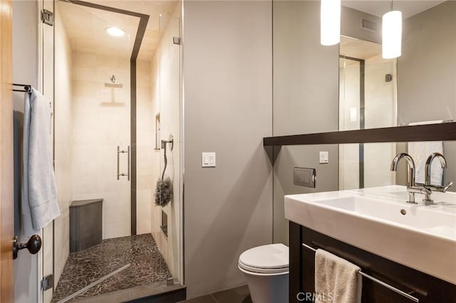 bathroom featuring vanity, toilet, and a shower with shower door