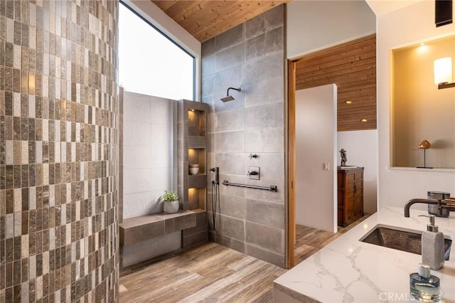 bathroom with a shower, wooden ceiling, tile walls, and vanity