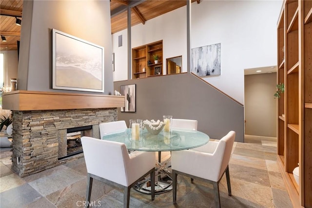 dining area with wooden ceiling, a fireplace, high vaulted ceiling, and beamed ceiling