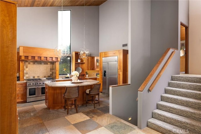 kitchen with a breakfast bar, a towering ceiling, premium appliances, wood ceiling, and a chandelier