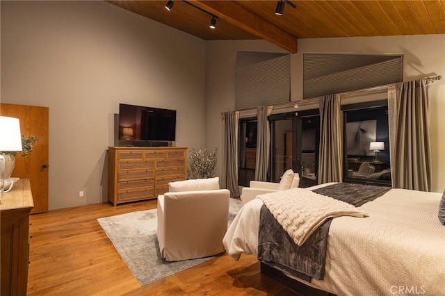 bedroom featuring a high ceiling, hardwood / wood-style floors, rail lighting, wooden ceiling, and beam ceiling