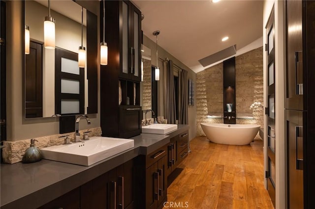 bathroom featuring hardwood / wood-style floors, a bathtub, vanity, and lofted ceiling